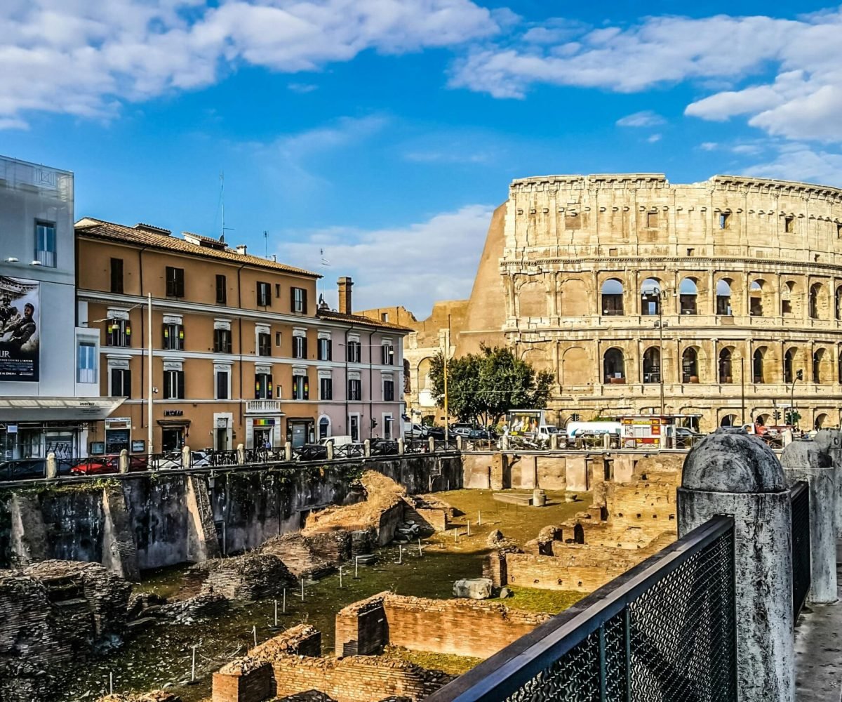 Daylight view of the historic Colosseum in Rome with vibrant city buildings.